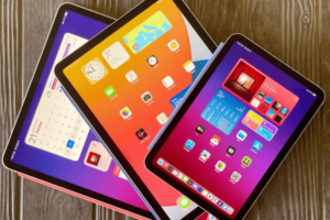 Three donated iPads prepared by Simple Home Solutions for North Harrow Community Library's kids coding class, shown stacked with vibrant screens on a wooden table.